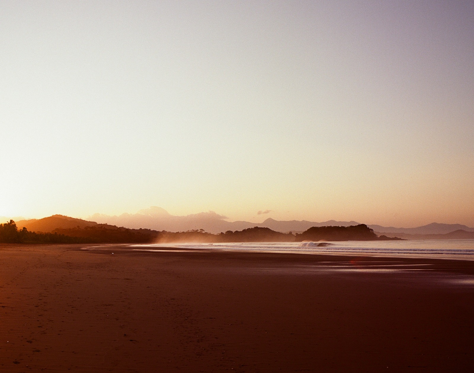 Sunset over the Pacific, jungle hills, and the beach at Playa Morrillo