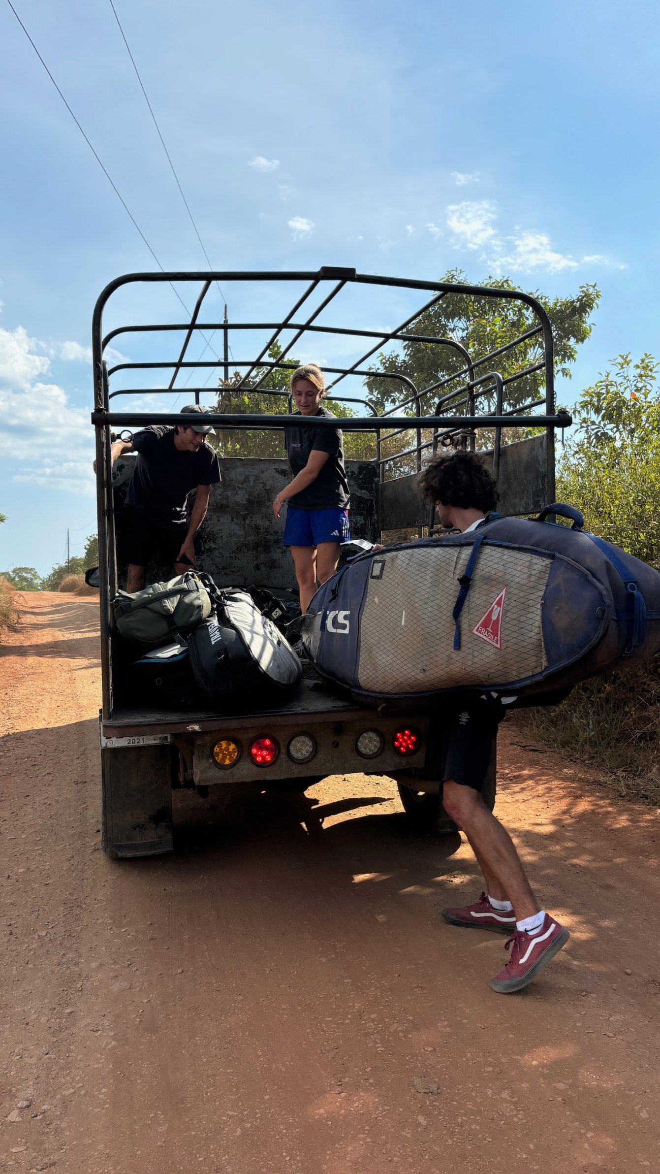 Board bags being loaded into a pickup on the road to Morrillo