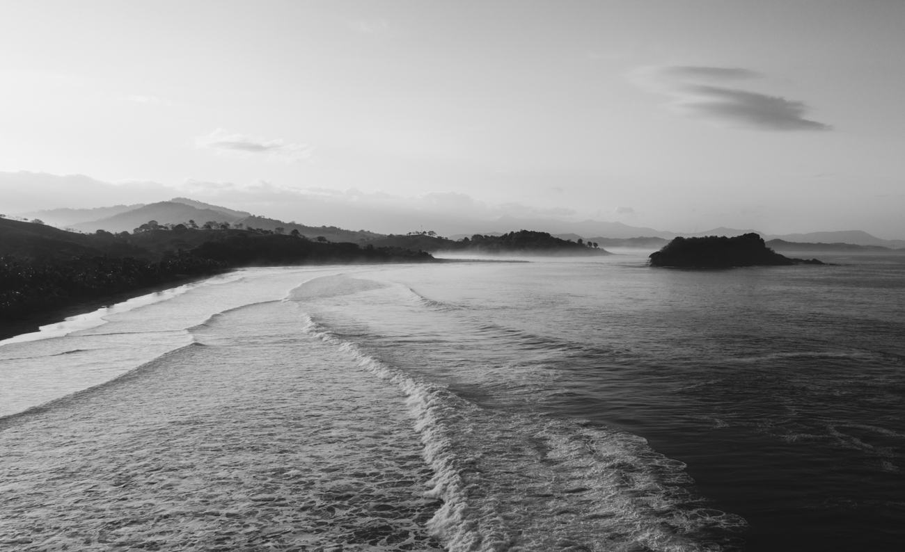 Black-and-white aerial view of waves wrapping into Playa Morrillo